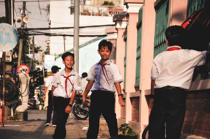 three boys standing on sidewalk